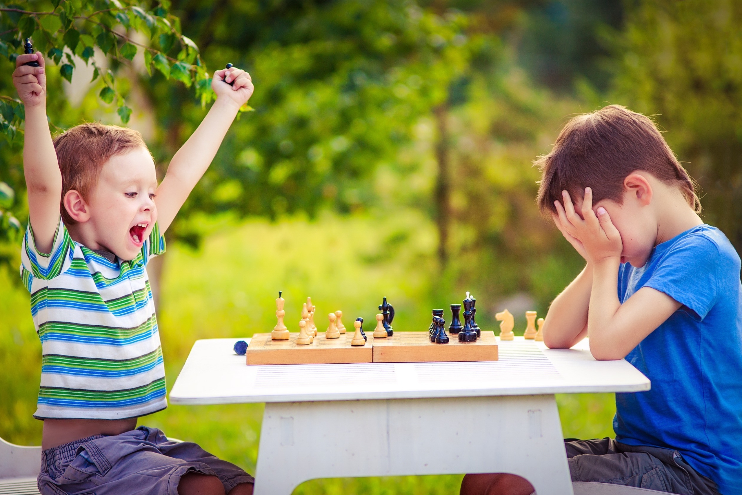two boys playing chess, one has just won the game and is celebrating