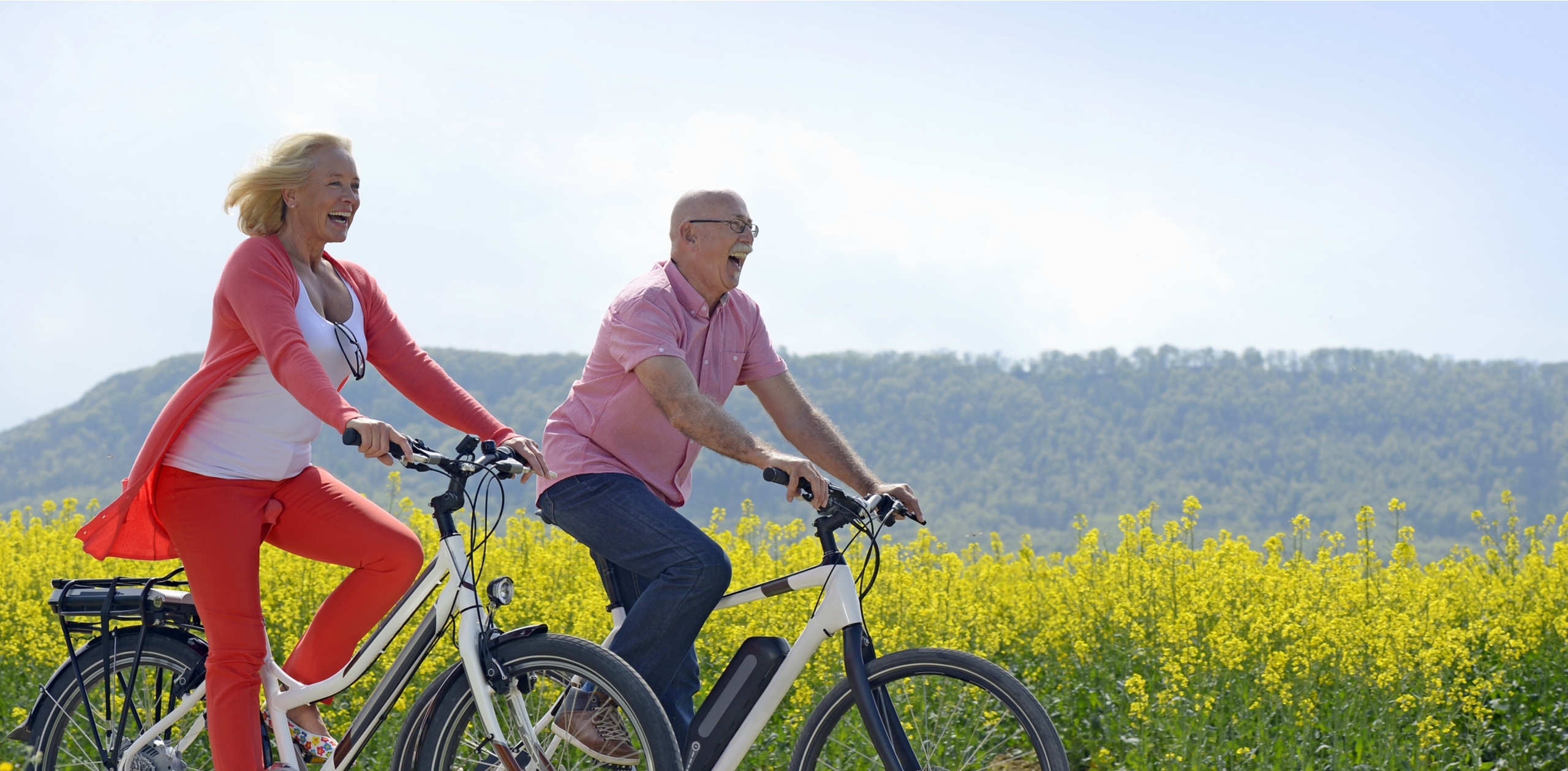 Older couple cycling past a field.