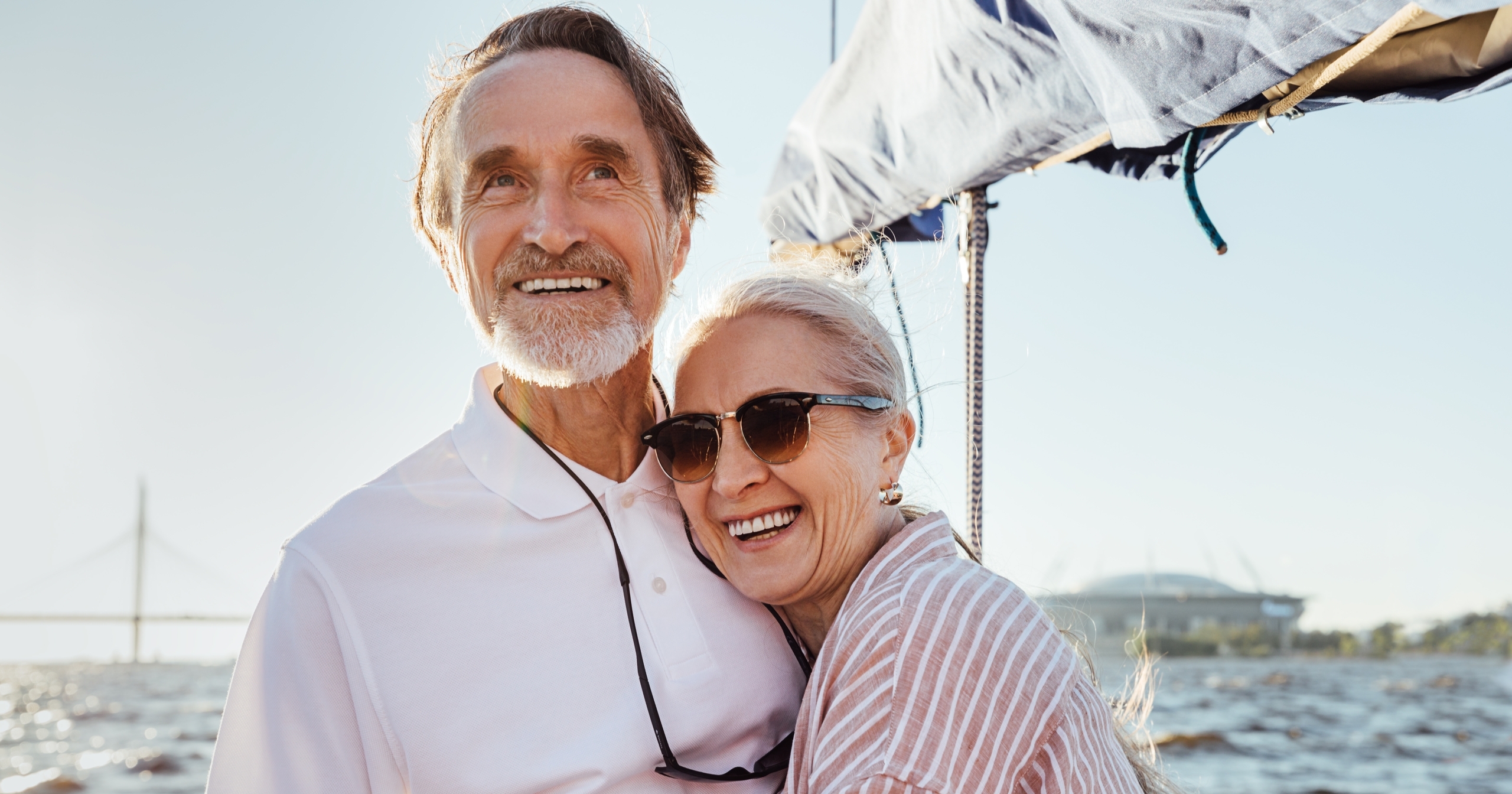 An older couple hugging on a boat.