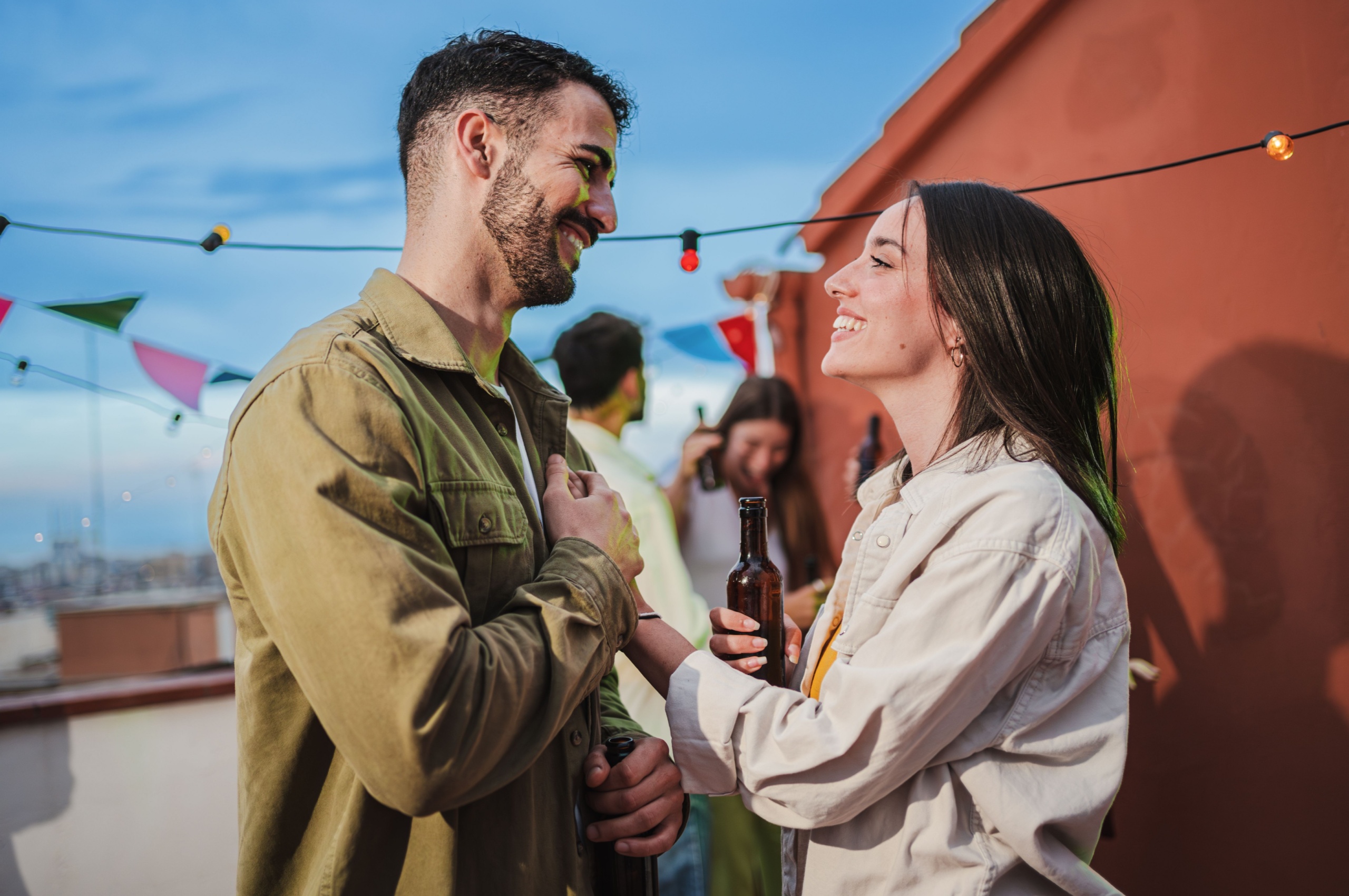 A young couple outside smiling at each other.