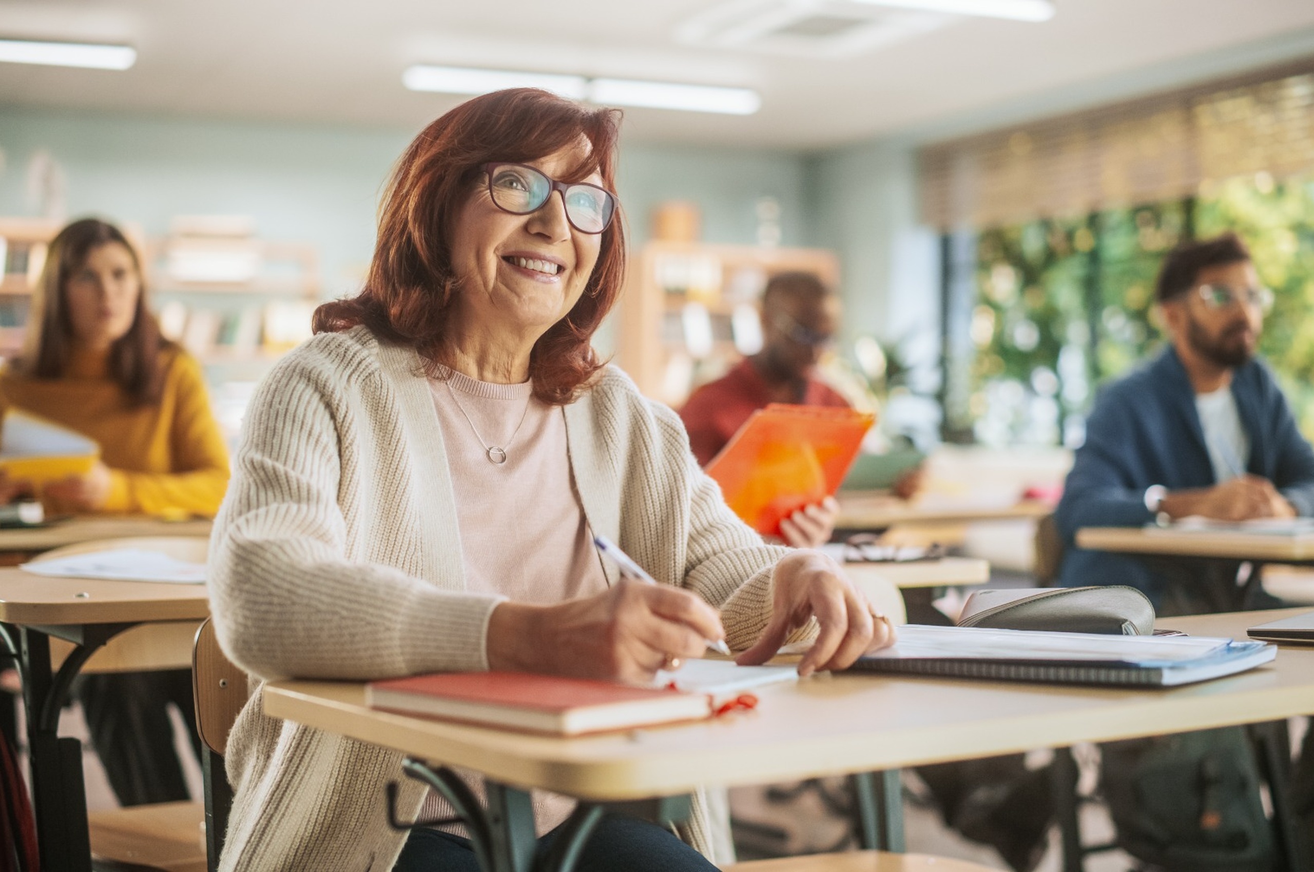 Happy senior woman taking notes in a classroom